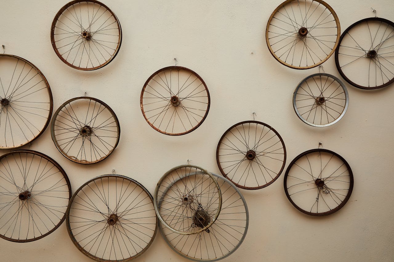 A collection of vintage bicycle wheels arranged on a wall, showcasing industrial art.
